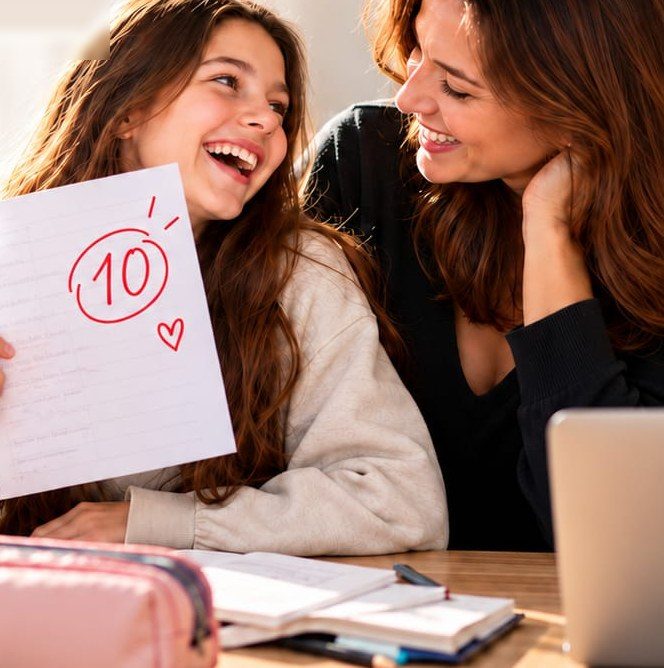 Elevă de gimnaziu care îi arată mamei, zâmbind, un test de matematică notat cu 10